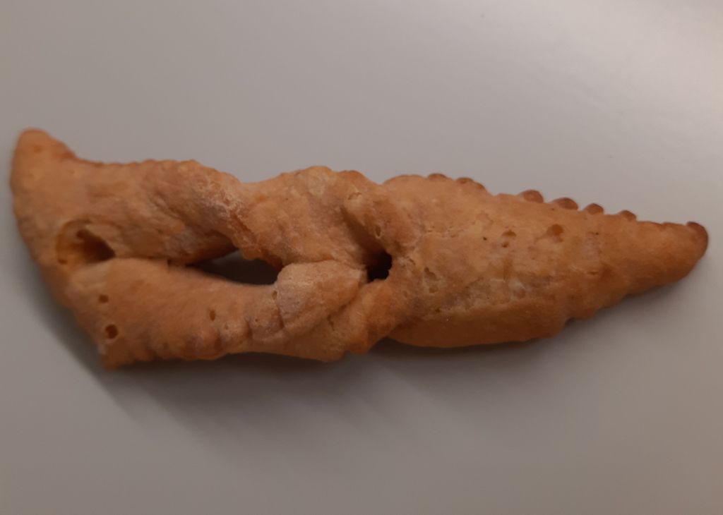 Das Foto zeigt ein längliches Teiggebäck, das rechts in einem Spitz ausläuft. Es hat in der Mitte einen Schlitz.