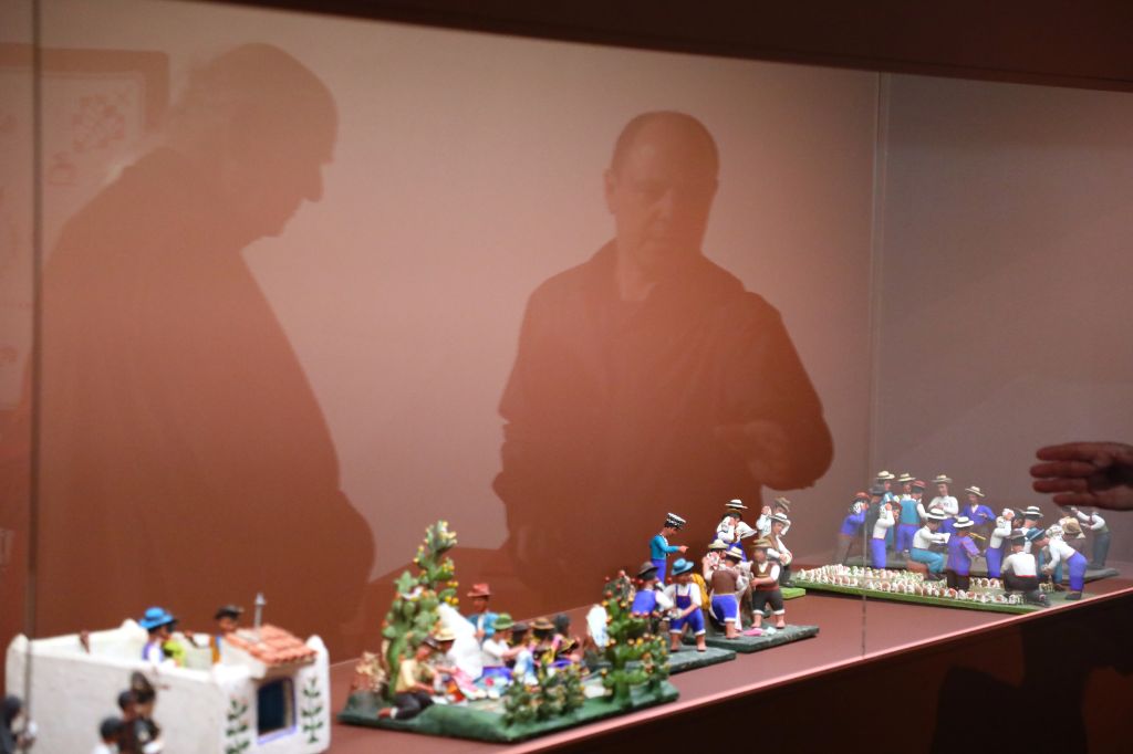 Auf einem Spiegel sind die Schatten von zwei Figuren zu sehen, während sie Miniaturen betrachten