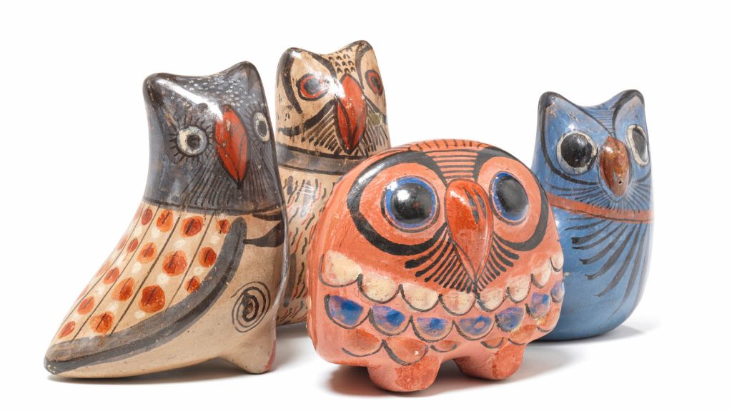 Bunte Keramikeulen in Rot, Gelb und Lila stehen nebeneinander auf weissem Hintergrund