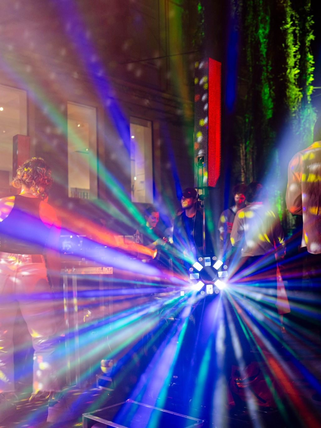 Auf einer tanzenden Partyszene strahlen bunte Lichter in alle Richtungen