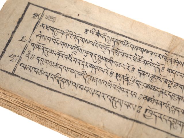 Alte tibetische Manuskriptseite mit handgeschriebenem Text in schwarzer Tinte auf vergilbtem Papier