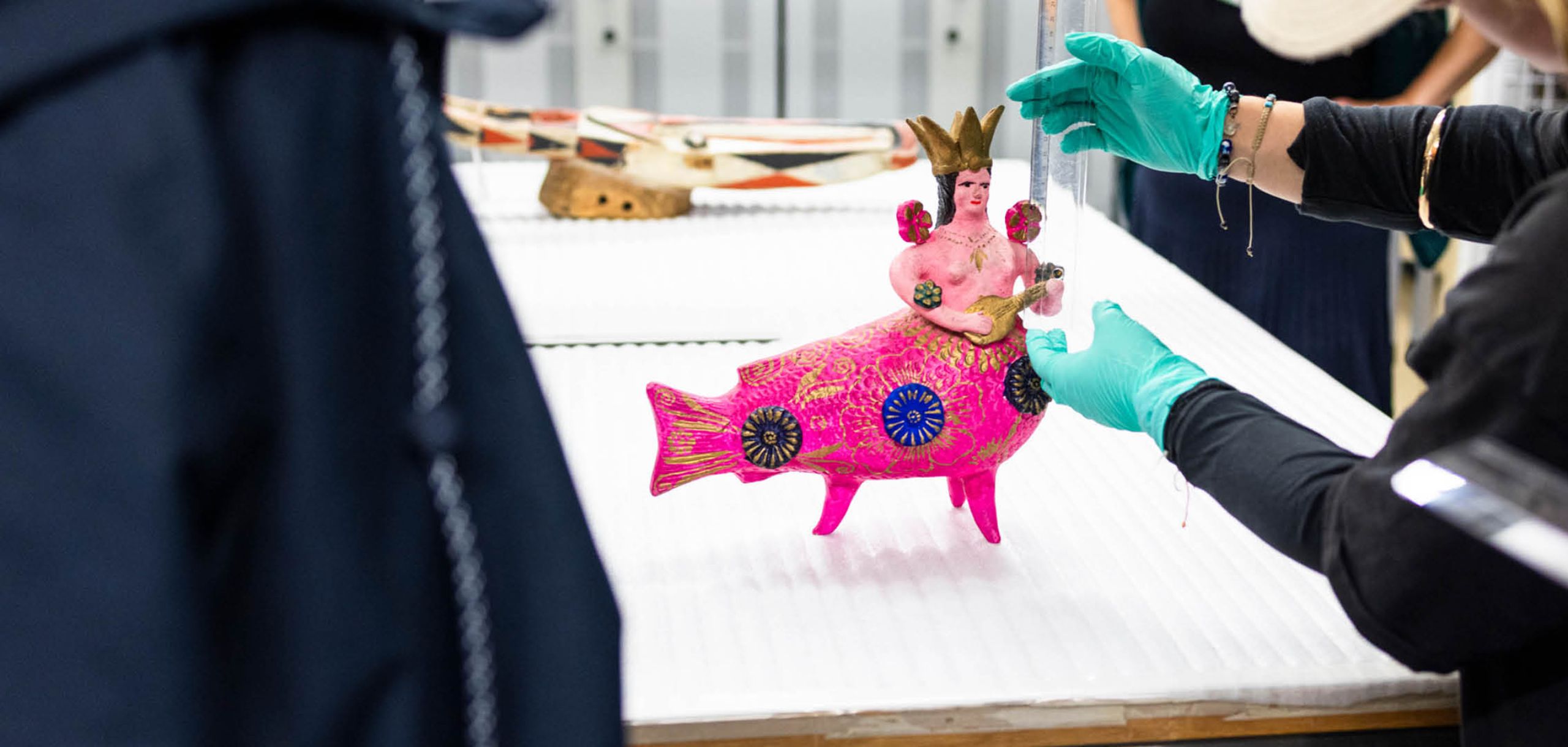 Une sculpture colorée et rose avec un corps de poisson et un torse humain est mesurée